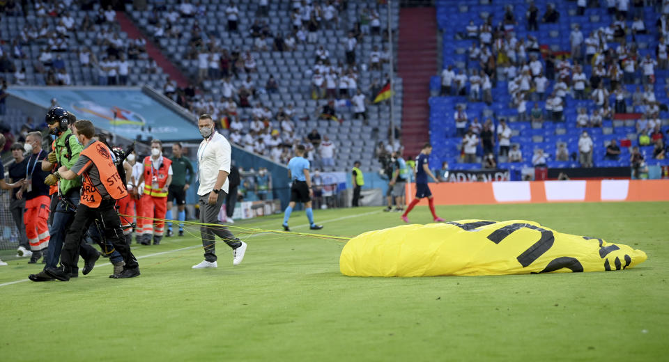 A protestor is lead of the pitch before the Euro 2020 soccer championship group F match between France and Germany at the Allianz Arena stadium in Munich, Tuesday, June 15, 2021. (Matthias Hangst/Pool via AP)