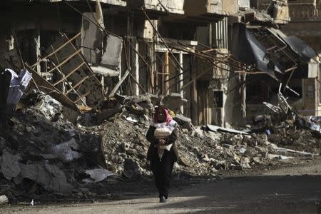 A man holds bread as he walks along a damaged street filled with debris in Deir al-Zor, eastern Syria February 19, 2014. REUTERS/Khalil Ashawi