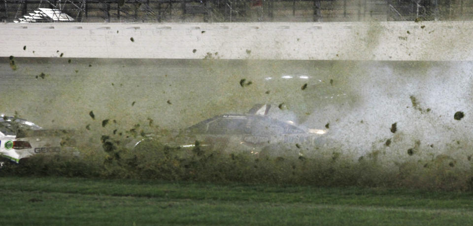 AJ Allmendinger (47) spins into the infield grass behind Casey Mears, left, during a NASCAR Sprint Cup Series auto race at Kansas Speedway in Kansas City, Kan., Saturday, May 10, 2014. (AP Photo/Colin E. Braley)