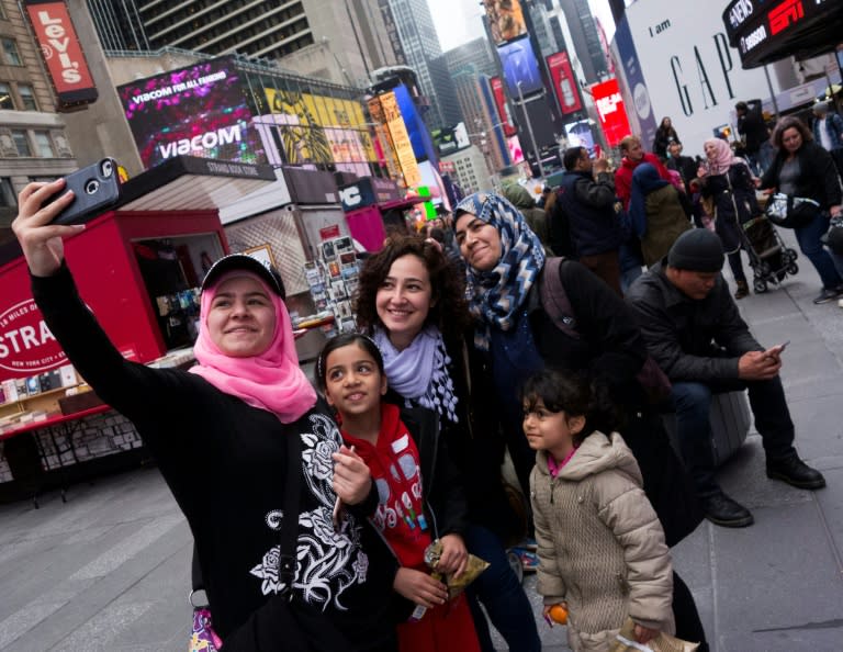 Syrian and Iraqi refugee families take selfies in Times Square during a tour of Manhattan in New York