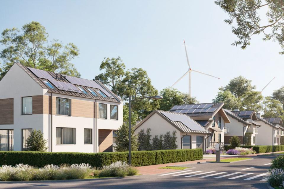 A view of houses with two wind turbines in the background.