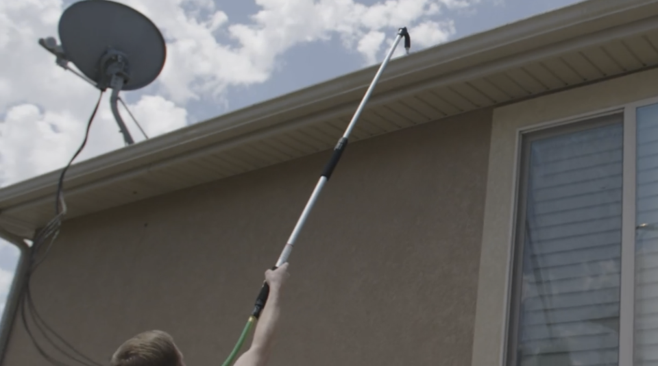 telescoping gutter wand being used to clean gutter