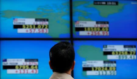 A man looks at a electronic board showing the Dow Jones average (top R) and NASDAQ average (top L) outside a brokerage in Tokyo, Japan, November 10, 2016. REUTERS/Toru Hanai