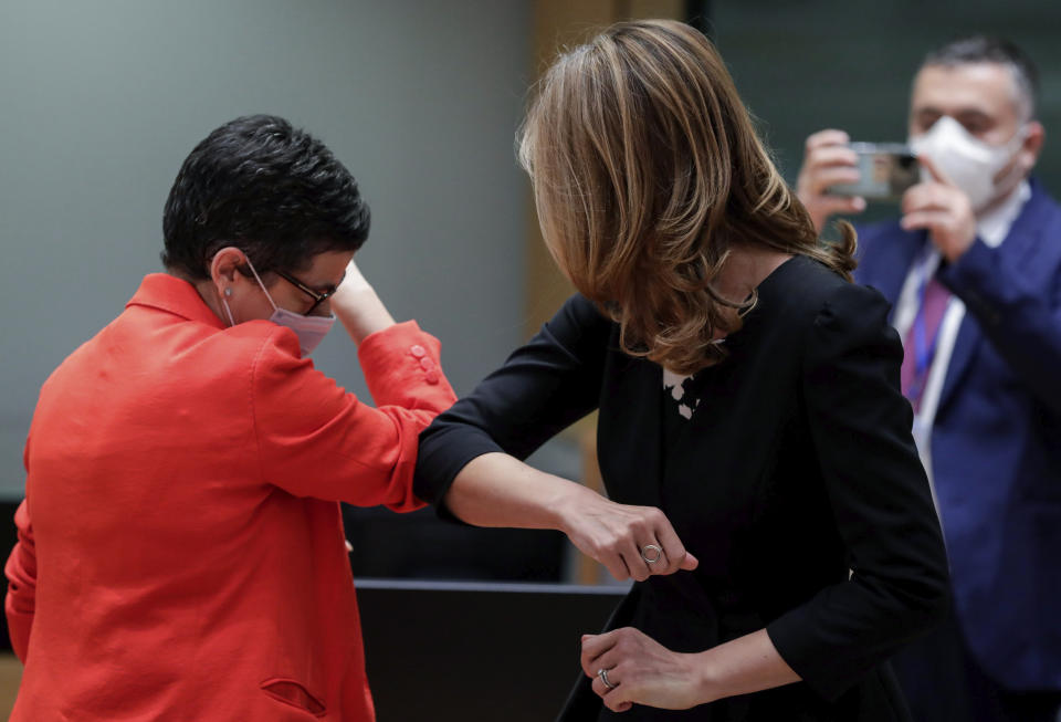 FILE - In this Monday, July 13, 2020 file photo, Spain's Foreign Minister Arancha Gonzalez, left, and Bulgaria's Foreign Minister Ekaterina Zharieva, center, greet each other with an elbow bump during a meeting of EU foreign ministers at the European Council building in Brussels. European Union leaders will meet face-to-face on Friday, July 17, 2020 for their summit as they try to carve up a potential package of 1.85 trillion euros among themselves. In perhaps the first such major meeting of leaders since the COVID-19 outbreak hit the world, the stakes were just too high for attendees not to look one another in the eye. (Stephanie Lecocq, Pool Photo via AP, File)