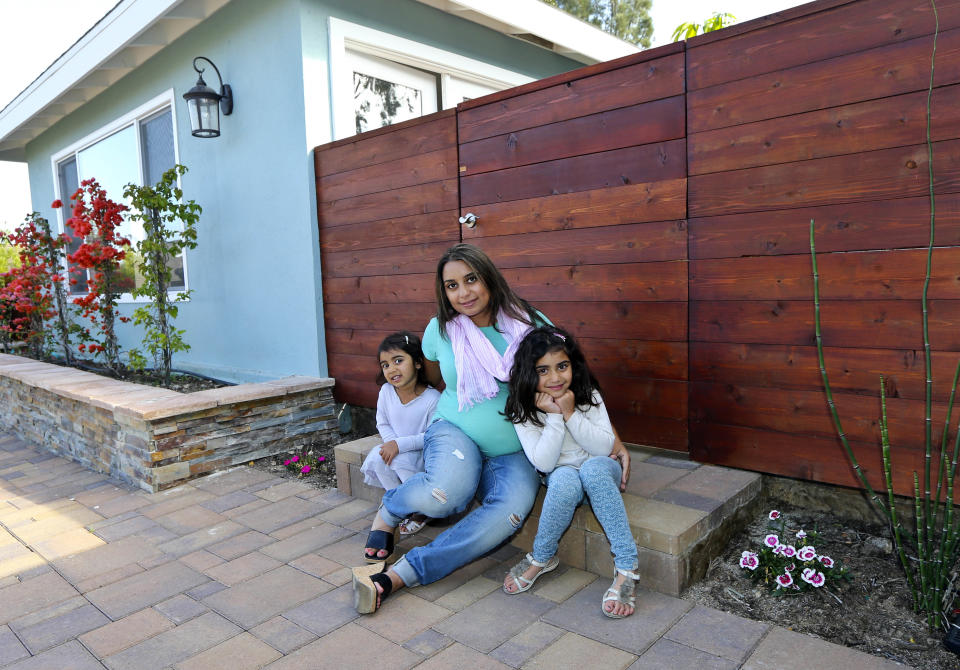 In this April 16, 2014 photo, Aniqa Jaswal poses with her daughters, Arissa, right, and Jayda on the front stoop of their home in La Jolla, Calif. Aniqa Jaswal and her husband in February bought the four-bedroom house that’s about 10 minutes from the beach. Once her husband’s management consulting business began flourishing, the couple felt comfortable enough after years of renting to buy their first home. (AP Photo/Lenny Ignelzi)