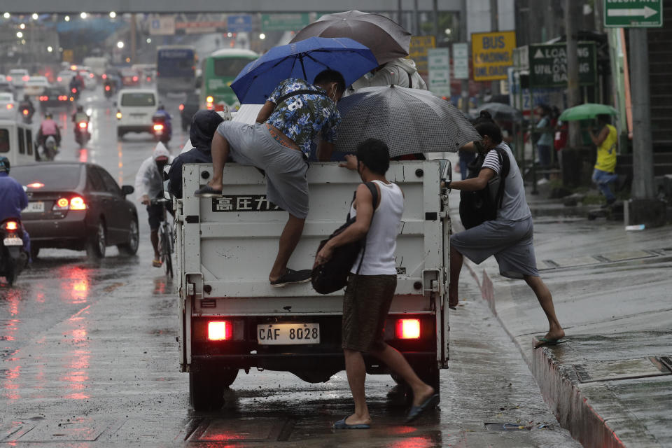 Workers climb on to a truck for a free ride as rain caused by Typhoon Vamco started to pour in Quezon city, Philippines on Wednesday, Nov. 11, 2020. Typhoon Vamco blew closer Wednesday to a northeastern Philippine region still struggling to recover from a powerful storm that left a trail of death and destruction just over a week ago, officials said, adding that thousands of villagers were being evacuated again to safety. (AP Photo/Aaron Favila)