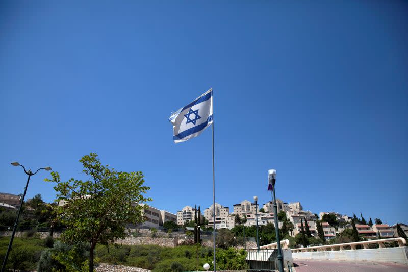 The Israeli national flag flutters as apartments are seen in the background in the Israeli settlement of Maale Adumim in the Israeli-occupied West Bank