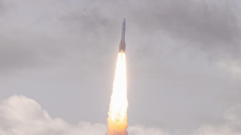 a large white rocket flies through the sky above a cone of flame