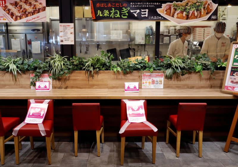 FILE PHOTO: Social distancing signs are place on a table and chairs at a restaurant in Japan's supermarket group Aeon's shopping mall as the mall reopens amid the coronavirus disease (COVID-19) outbreak in Chiba