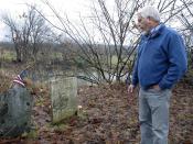 In this Dec. 10, 2019, photo, Don Mason, chairman of the Weybridge, Vt., selectboard looks at gravestone of Revolutionary War soldier William Haven, who is buried in a cemetery near the edge of an eroding river bank in Weybridge, Vt. Rising seas, erosion and flooding from worsening storms that some scientists believe are caused by climate change are putting some older graveyards across the country at risk. (AP Photo/Lisa Rathke)