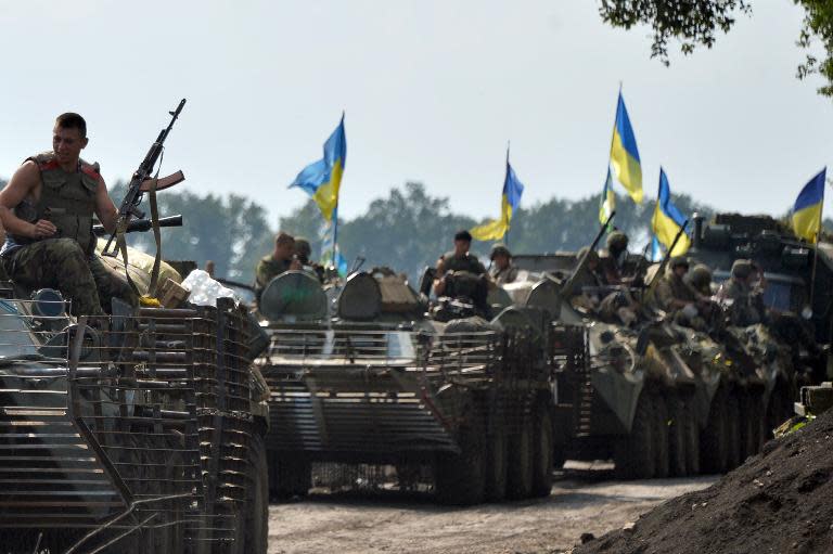 Ukrainian servicemen sitting atop armored personnel carriers travel near the eastern city of Slavyansk on July 11, 2014