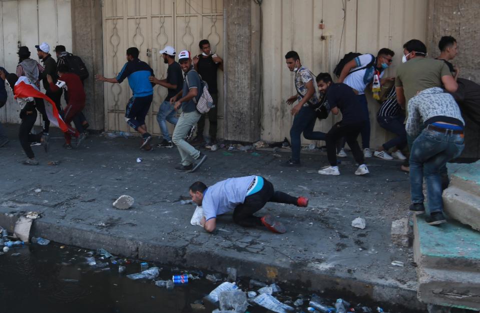 Anti-government protesters run for cover while security forces fire live ammunition in the air to disperse protesters, during ongoing protests, in Khilani Square, Iraq, Monday, Nov. 11, 2019. (AP Photo/Khalid Mohammed)