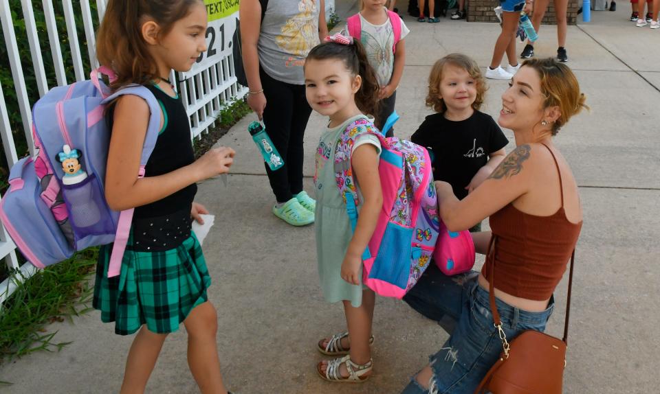Elizabeth Kinzel with her daughter Rosemari', who is starting second grade, and Scarlett, who starts kindergarten next week, are pictured at Discovery Elementary in Palm Bay. Brevard County Schools returned to class on Thursday.