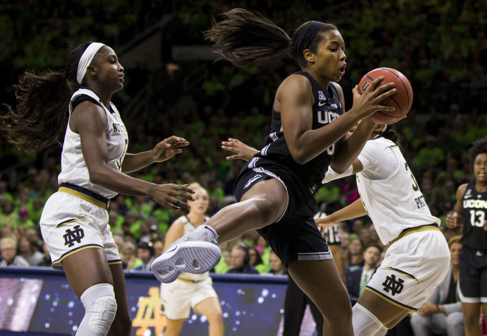 Connecticut's Megan Walker, center, grabs a rebound between Notre Dame's Jackie Young, left, and Danielle Patterson during the first half of an NCAA college basketball game Sunday, Dec. 2, 2018, in South Bend, Ind. (AP Photo/Robert Franklin)