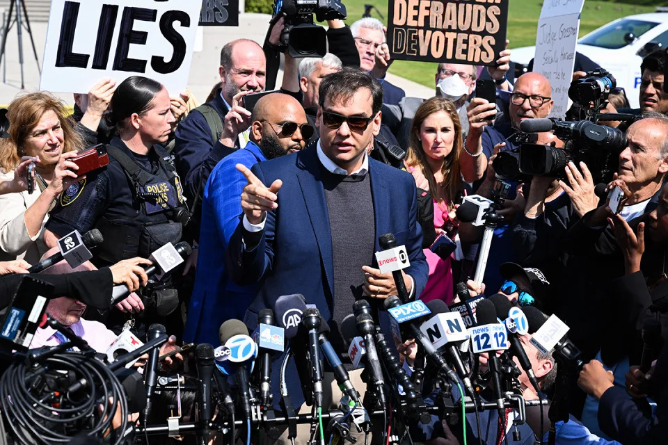 Rep. George Santos leaves federal court and faces a gaggle of reporters and mics.