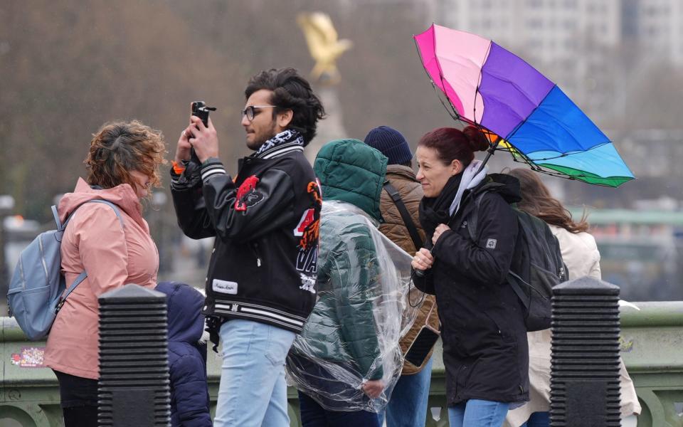 People in the rain walking along Westminster Bridge in London