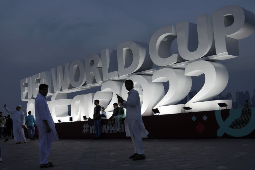 People pose for a photograph with a sign reading in English" Fifa World Cup, Qatar 2022.