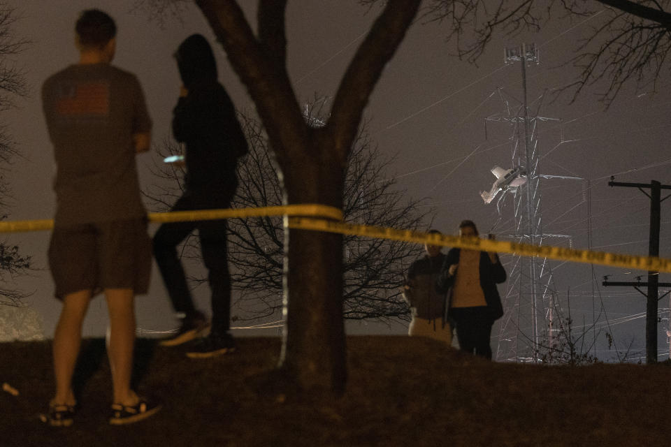 People observe a small plane resting on live power lines after crashing, Sunday, Nov. 27, 2022, in Montgomery Village, a northern suburb of Gaithersburg, Md. (AP Photo/Tom Brenner)