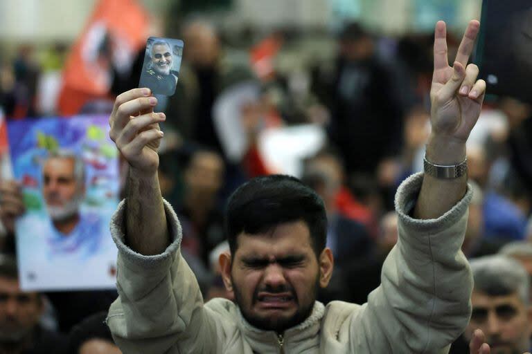 Un joven iraní muestra una foto del alto comandante iraní asesinado Qassem Soleimani durante la ceremonia de conmemoración del aniversario de su asesinato en la capital iraní, Teherán, el 3 de enero de 2024. (ATTA KENARE / AFP)