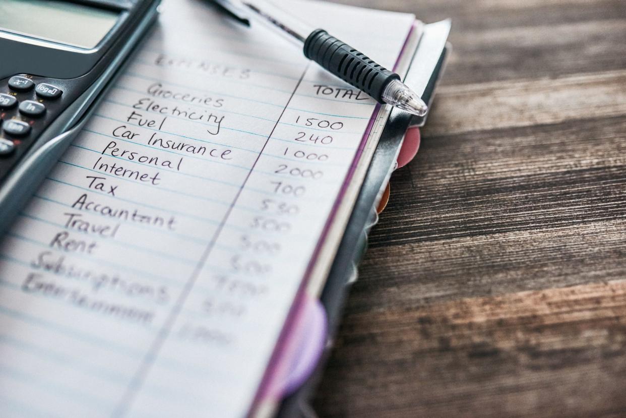 Shot of a notebook with a budget written on it and a calculator on a desk at home