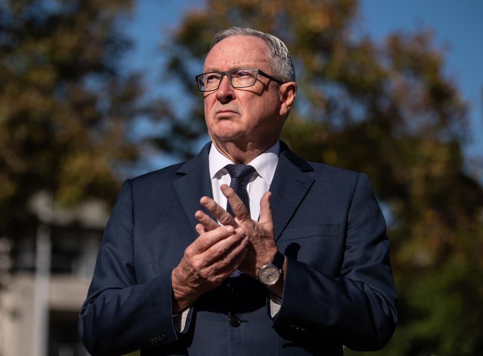 NSW Minister for Health Brad Hazzard has an angry expression on his face as he stands outside. 