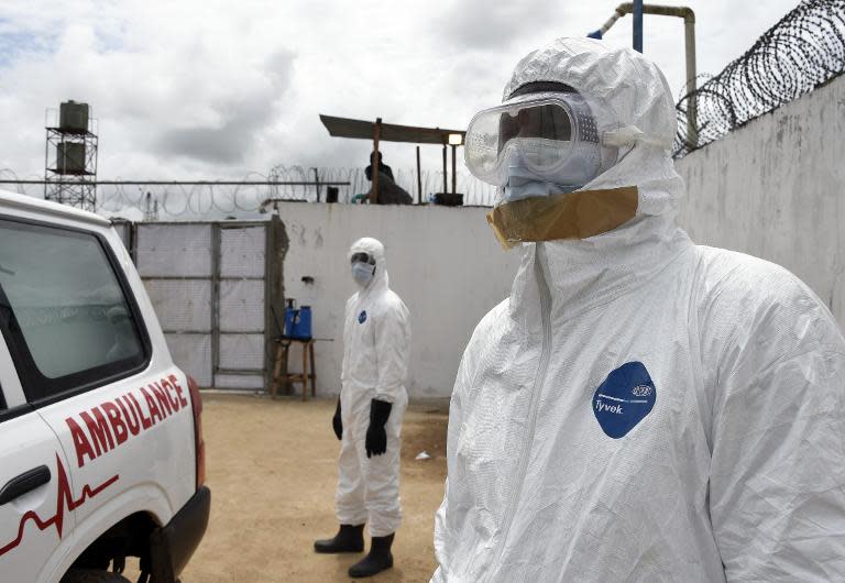 Health workers in protective suits look at an ambulance upon its arrival at Island Hospital in Monrovia on September 30, 2014