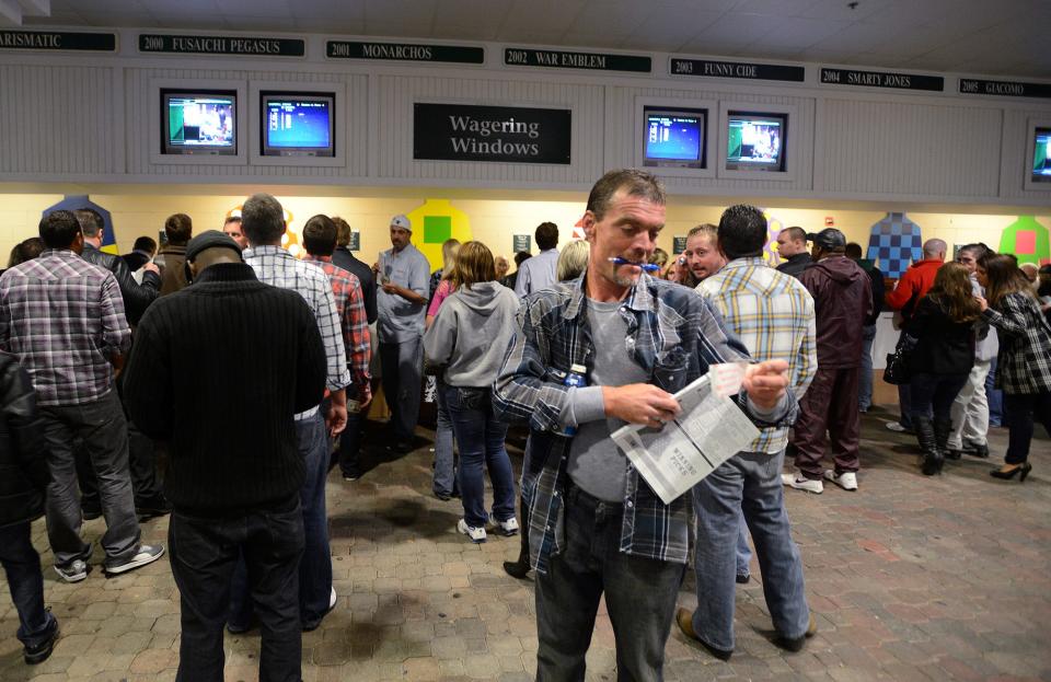 Rob Gwinn of Louisville checks his tickets by the betting window during the opening night of Churchill Downs’ 2013 Spring Meet.