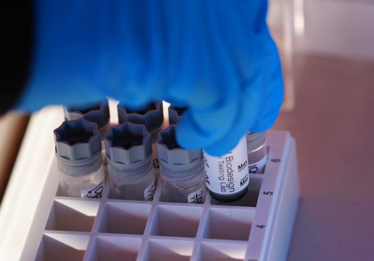 Mariana Abasta, a test administrator, places a vial into a tray at a saliva COVID-19 testing site, operated by Arizona State University and the Arizona Department of Health Services, on Jan. 26, 2022, in Scottsdale, Arizona.