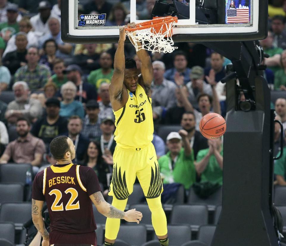 Oregon forward Kavell Bigby-Williams hangs on the rim after dunking as Iona forward Taylor Bessick, left, looks on during the first half of a first-round game in the men's NCAA college basketball tournament in Sacramento, Calif., Friday, March 17, 2017. (AP Photo/Steve Yeater)