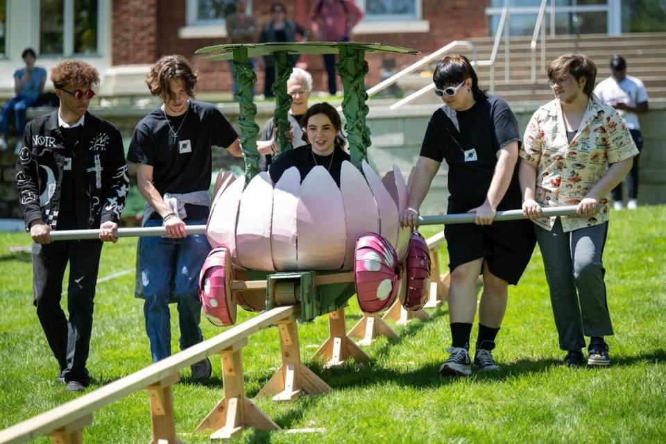 With some help from her classmates, Grace Ozzello, center, of Council Bluffs, Iowa, rode the lotus flower vehicle for the annual Rail Day event on Wednesday at the Kansas City Art Institute. Ozzello worked with Daniel Ifarig, right, of Kansas City to create their vehicle.