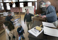 FILE - In this March 11, 2008, file photo, moderator Dick Kipperman, right, accepts a resident's ballot during the annual town meeting in Springfield, N.H. The COVID-19 pandemic is disrupting New England town meetings in 2021, a tradition where citizens gather to debate and decide on local issues. (AP Photo/Jim Cole)