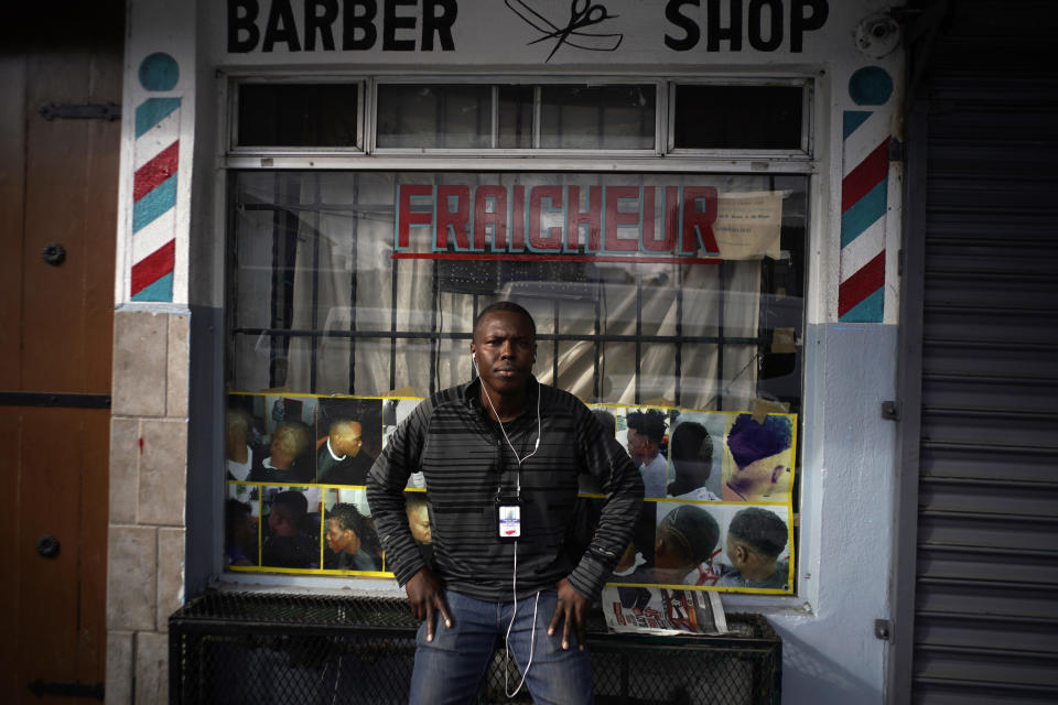 Philocles Julda, de 44 años, posa para una foto frente a una barbería haitiana en Tijuana, México, el jueves 22 de noviembre de 2018. (AP Foto/Ramón Espinosa)