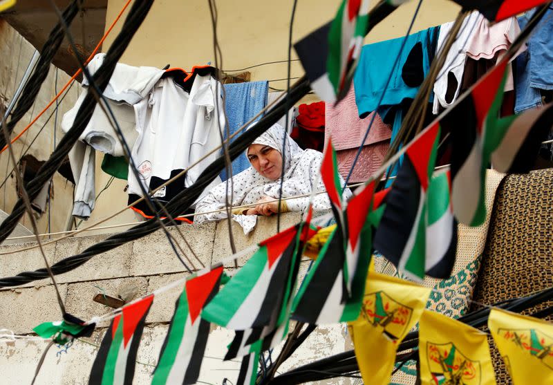 A woman is seen through flags and electricity cables in Shatila Palestinian refugee camp in Beirut suburbs