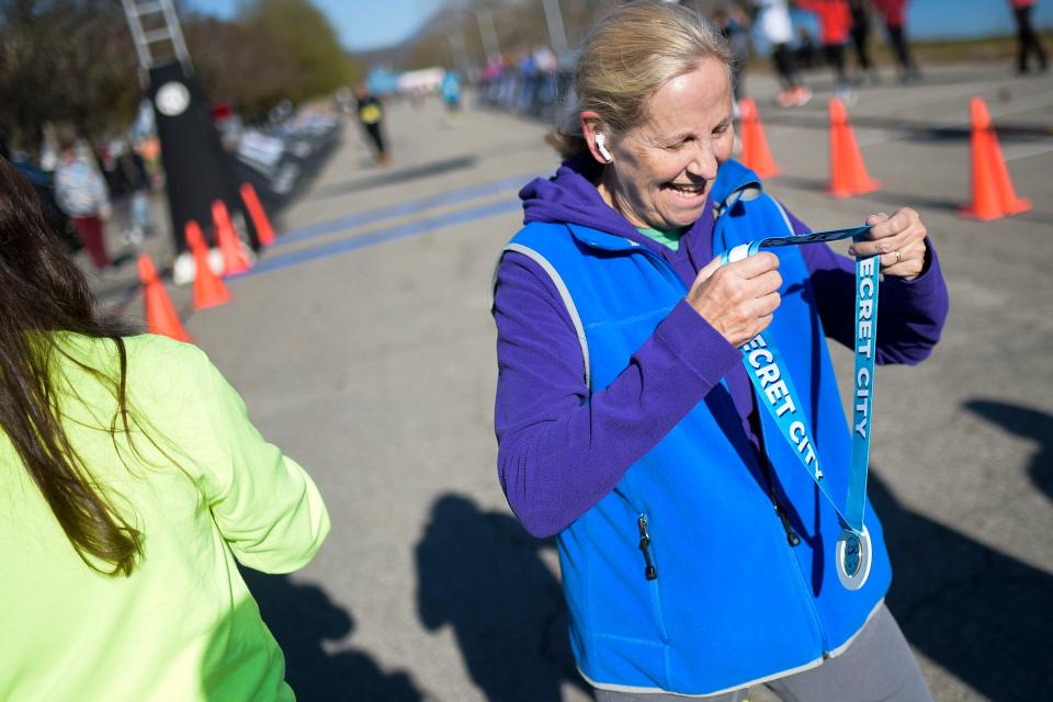 Ann Schubert receives her medal after crossing the finish line at the Secret City Half Marathon.