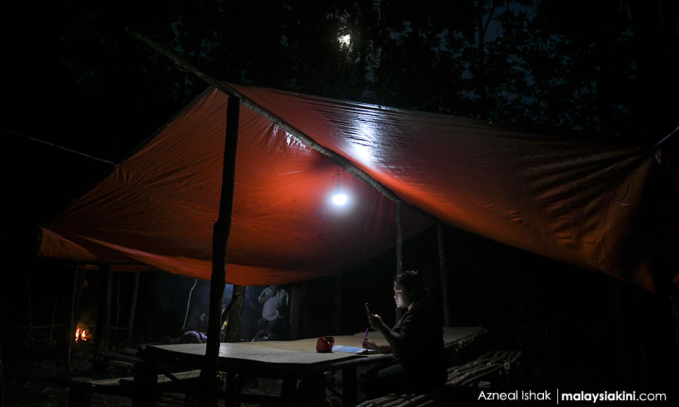 UiTM Segamat student Zarina Ramli, 19, attends online classes into the night at the hut.