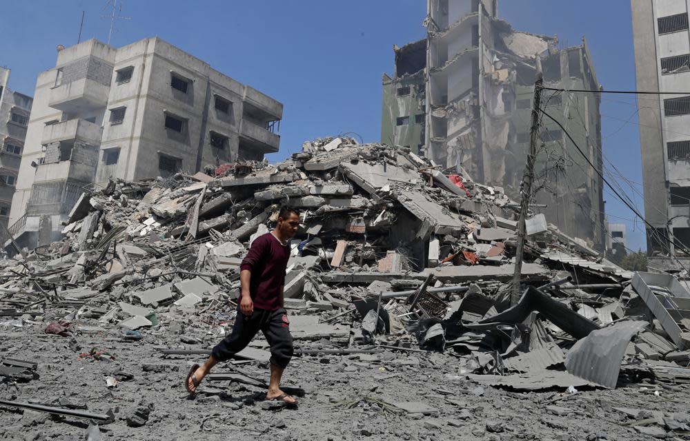<p>A man walks past the rubble of the Yazegi residential building that was destroyed by an Israeli airstrike, in Gaza City, Sunday, 16 May</p> (AP Photo/Adel Hana)
