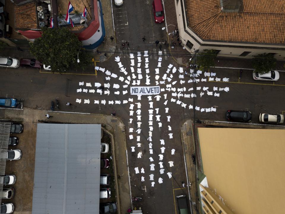 In this Monday, May 20, 2019 photo, the white coats of doctors lie on the street around the Spanish message "No to the veto," directed at President Mario Abdo Benítez, asking him to not veto a proposed law that would allow doctors, from both the public and private sectors, to partially retire after 25 years of work, in Asuncion, Paraguay. Doctors argue their medical studies keep them from starting work and entering the government pension system until years after professionals in other industries. Currently, workers are eligible for a government pension after age 65. (AP Photo/Jorge Saenz)