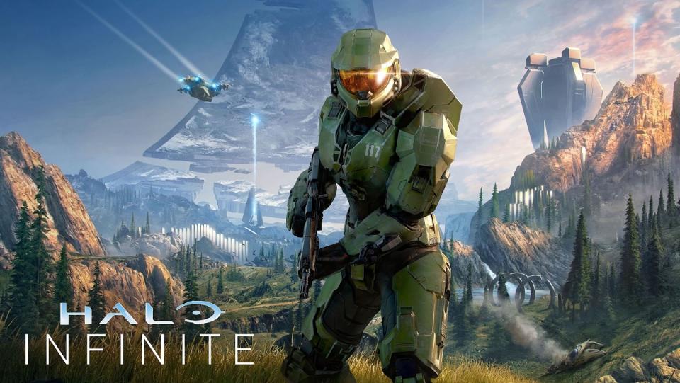 Master Chief stands in the center of the image brandishing a blaster rifle, as the familiar sights and landscape of the planet Halo surrounds him.