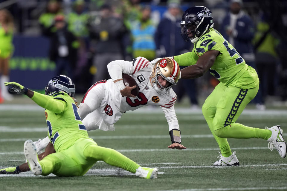 Seattle Seahawks linebacker Darrell Taylor (52) and linebacker Boye Mafe (53) sack San Francisco 49ers quarterback Brock Purdy (13) during the first half of an NFL football game, Thursday, Nov. 23, 2023, in Seattle. (AP Photo/Stephen Brashear)