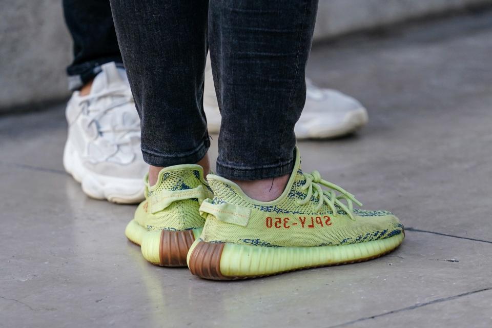 A person wears yellow "053-YLPS" adidas Yeezy sneaker