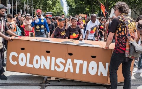 A group of Aboriginals stand in front of a a mock coffin with 'Colonisation' written on it on Australia Day - Credit: Anadolu Agency