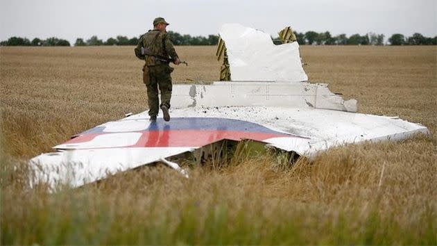 A soldier stands on the jet's tail marked with the Malaysian Airlines insignia laying in a corn field. Photo: Reuters.