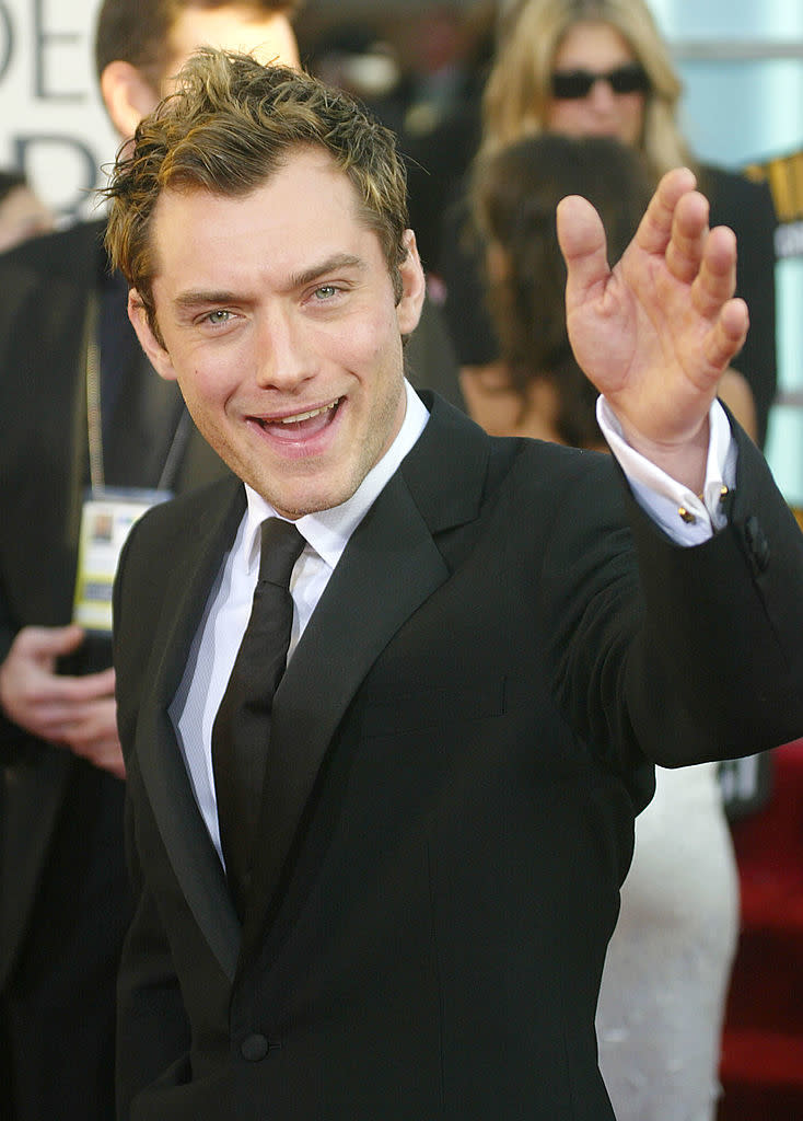 Close-up of Jude smiling and waving in a suit and tie