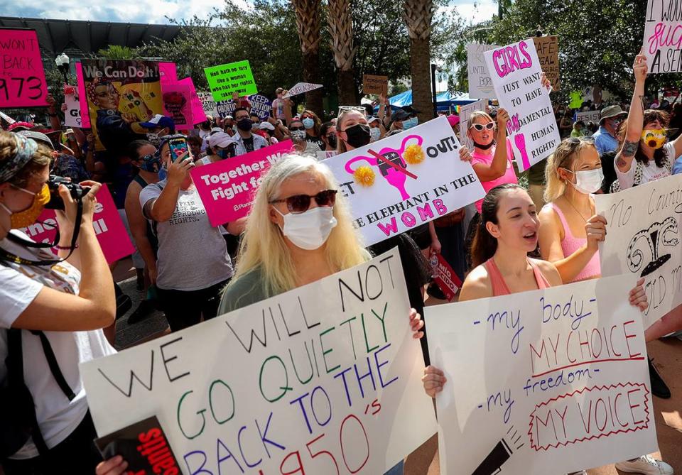 Participantes agitan carteles mientras caminan hacia el Ayuntamiento de Orlando durante la Marcha por el Acceso al Aborto, el sábado 2 de octubre de 2021, en Orlando.