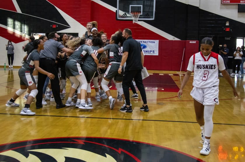 CORONA, CA - JUNE 10, 2021: Corona Centennial Londynn Jones (3) walks off the court as Mater Dei teammates surround Nalani White (10) after White scored the game winning shot in the last seconds to beat Corona Centennial in overtime to win the Southern Section Open Division Championship on June 10 2021 in Corona, California.(Gina Ferazzi / Los Angeles Times)