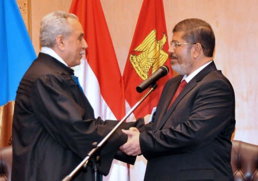 In this handout picture made available by the Egyptian presidency, Egyptian President Mohamed Morsi (R) shakes hands with Faruq Sultan, head of the presidential election commission, after taking the oath of office at his swearing-in ceremony at the Constitutional Court in Cairo