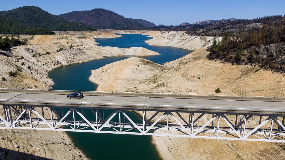 FILE - A car crosses Enterprise Bridge over Lake Oroville's dry banks on May 23, 2021, in Oroville, Calif. Months of winter storms have replenished California's key reservoirs after three years of punishing drought. (AP Photo/Noah Berger, File)