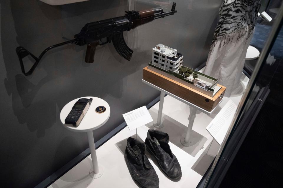 A model of the house where a precision counterterrorism operation killed al-Qaida's leader Ayman al-Zawahri is displayed below a rifle used by Michael Spann, the first American killed in Afghanistan, in the refurbished museum at the Central Intelligence Agency headquarters building in Langley, Va.