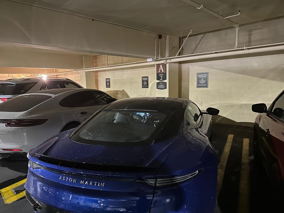 A blue Aston Martin car parked in a parking garage.
