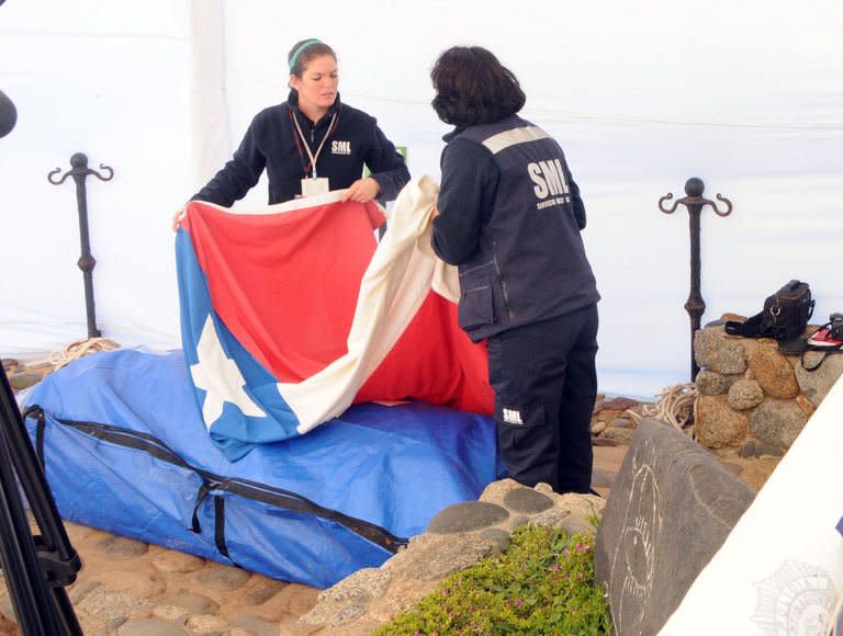 Coroner's office personnel cover the coffin of Chilean poet Pablo Neruda with the Chilean flag, in Isla Negra, on April 8 , 2013. Neruda's remains were exhumed Monday to determine if he died of cancer or was poisoned by the Pinochet dictatorship he strongly opposed